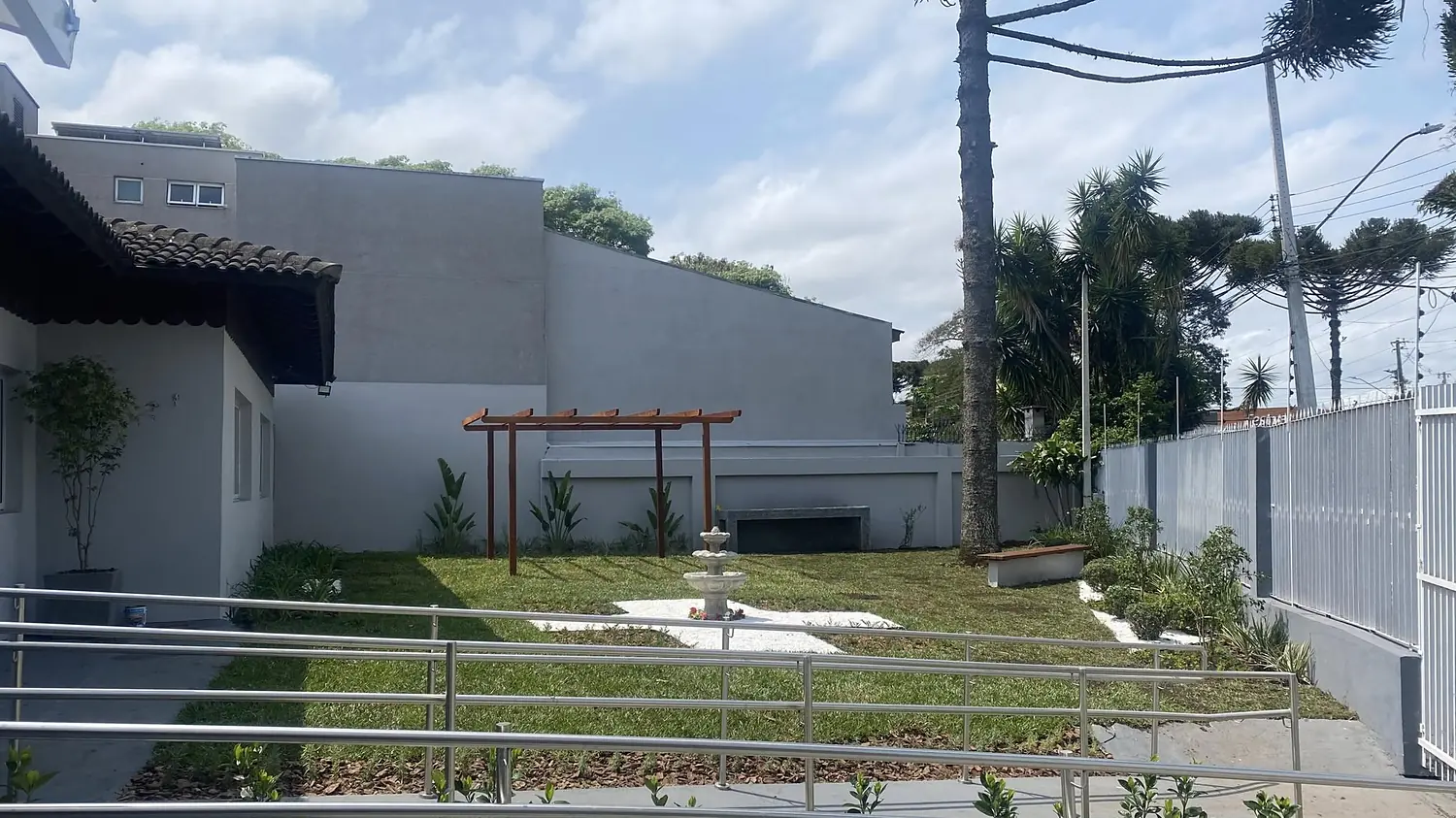 Jardim visto da rampa de acesso, com araucária e chafariz